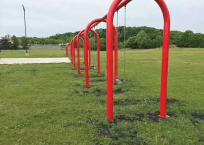 glimpses of rubber grass mats with grass growing through under a red swing set