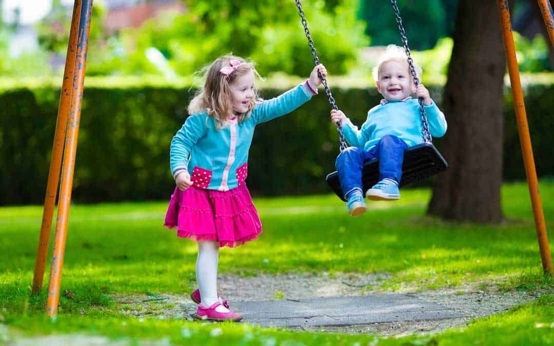 two kids playing on a swing in the backyard