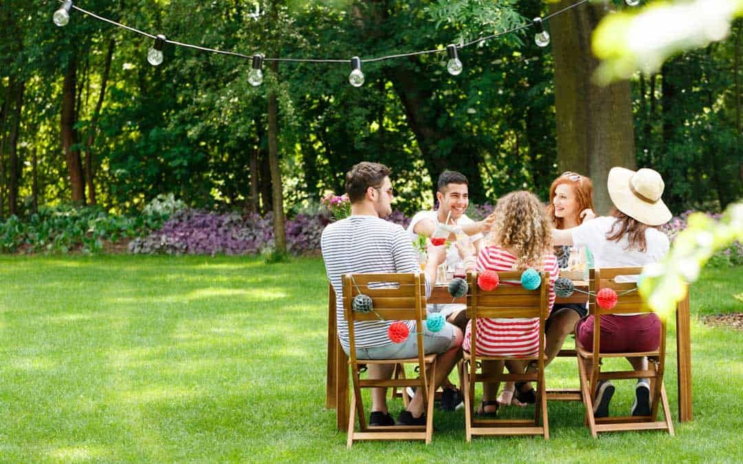 friends seated around a table in a backyard