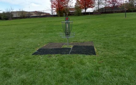 disc golf basket with grass mats played around the hole for protection