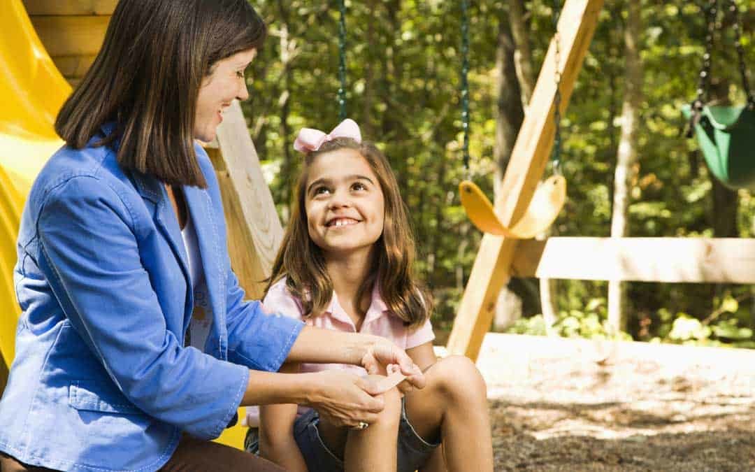 mom putting a bandaid on her child at the playground