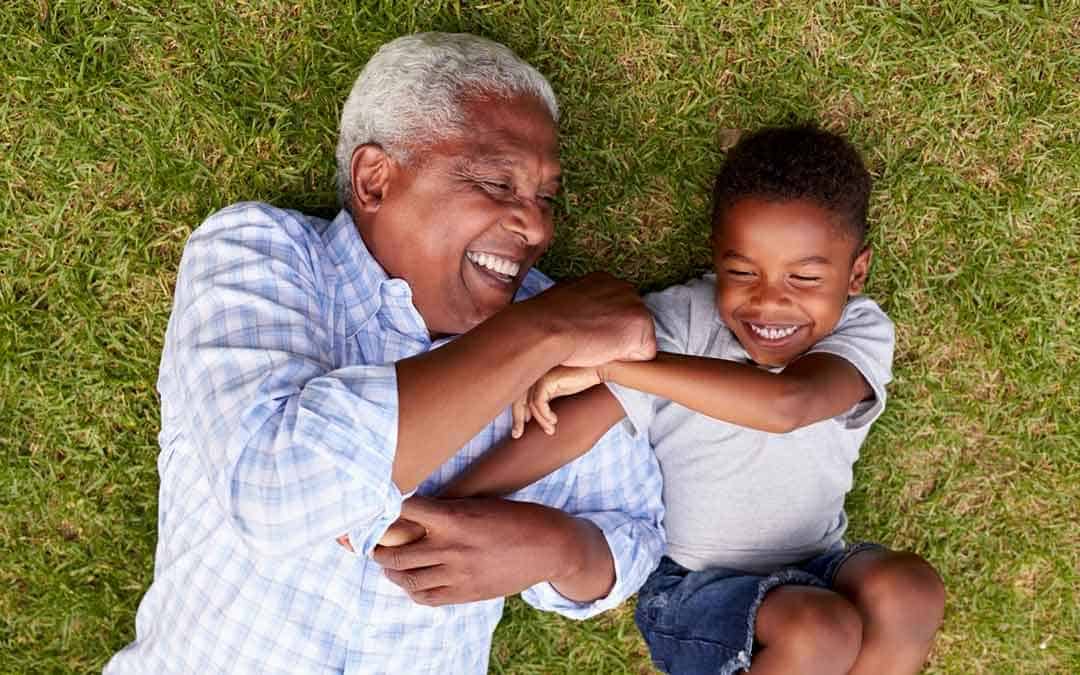 grandfather and grandson playing in backyard on grass protected by grass mats