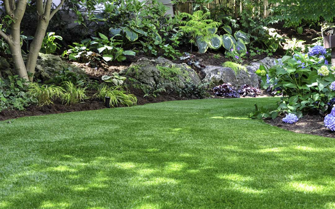 beautiful green yard with a garden and stone bed surrounding the yard