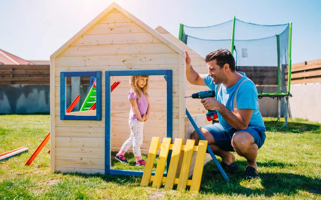 a dad and his daughter building a playhouse playground in the backyard of their home