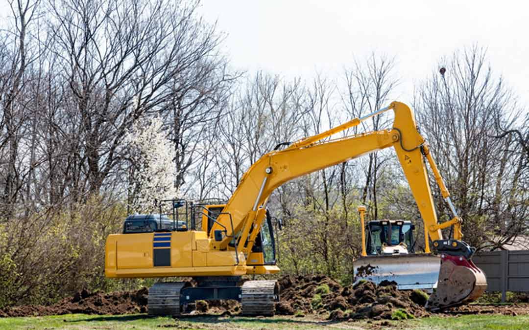 a yellow backhoe digging in a residential backyard